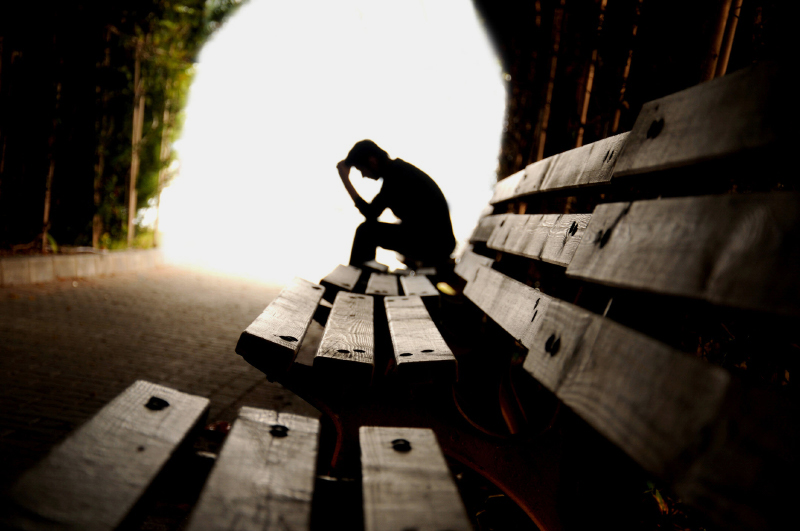 Person sitting alone on a bench in a tunnel.