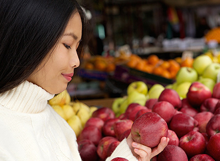 Young woman in grocery store looking at apples.