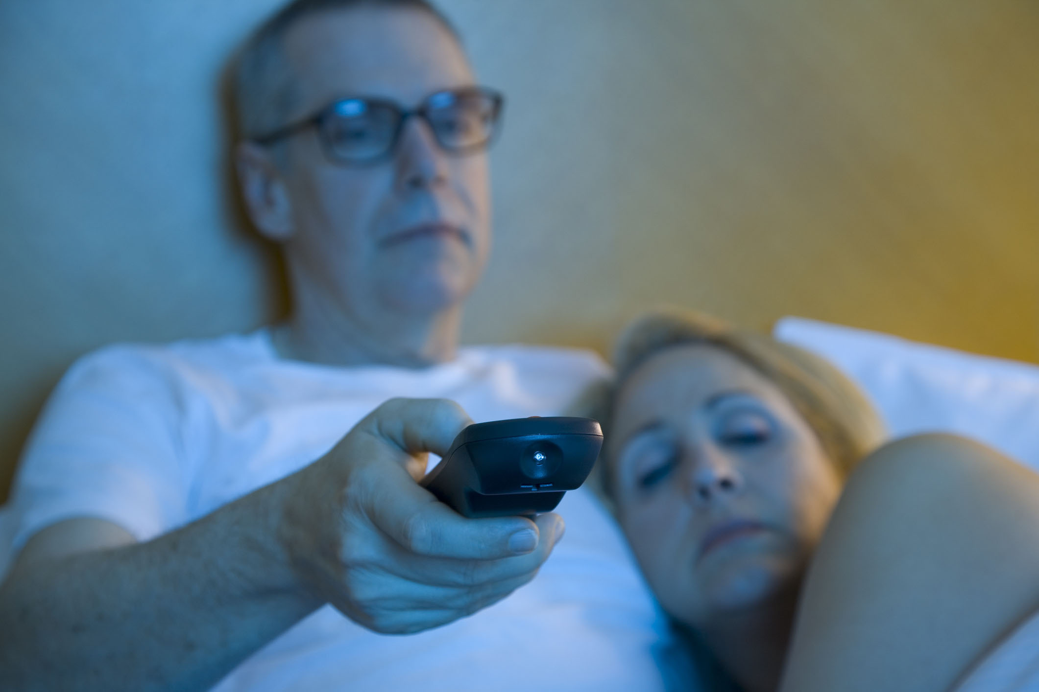 Sleepy couple watching television in bed