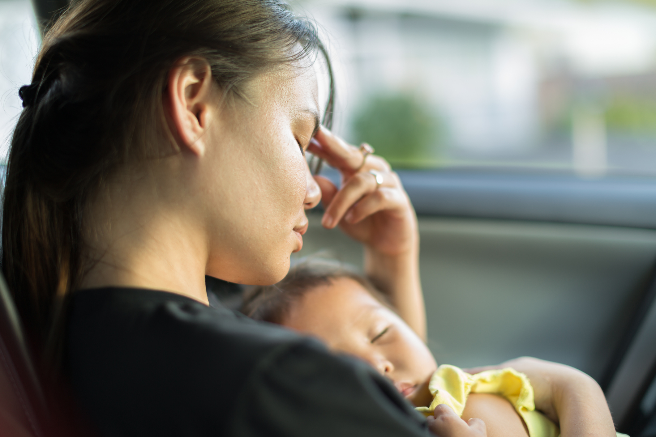 Stressed mom trying to nap with her baby in the car