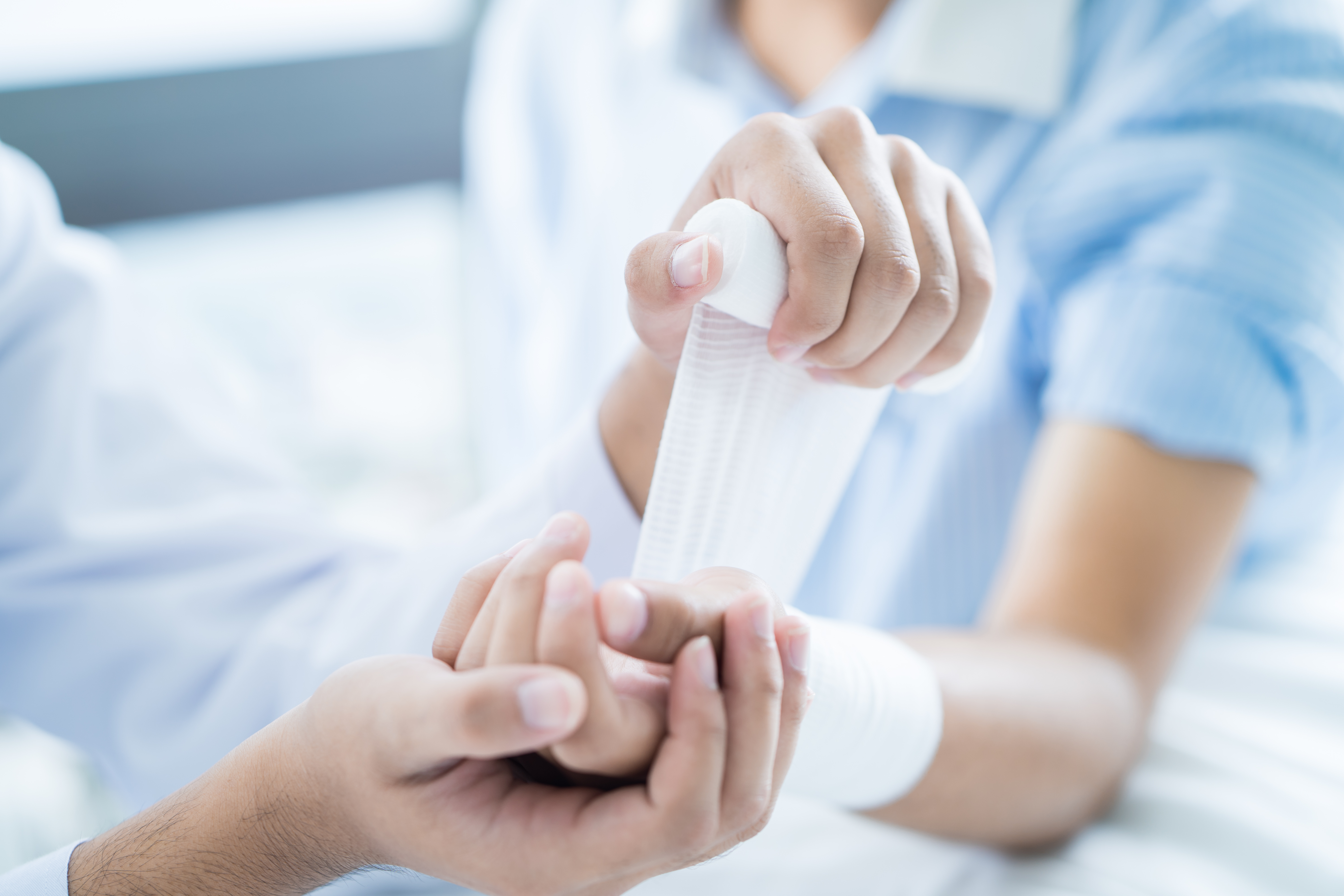 Close up of a doctor bandaging the upper limb on a patient