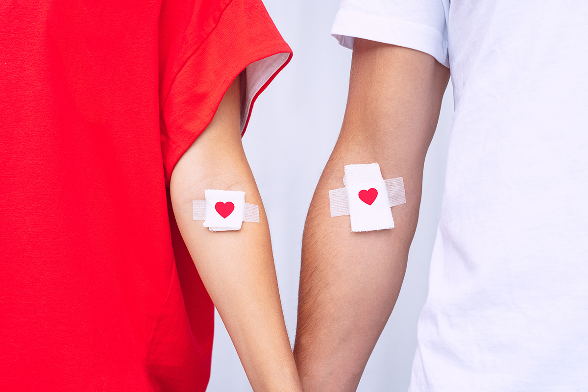 Blood donors showing their bandages with hearts on them, after blood donation.