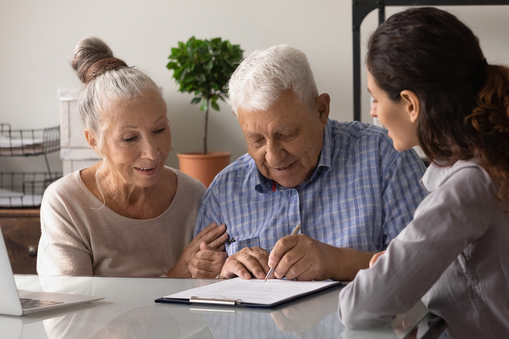 Older adult signing paperwork with his family.