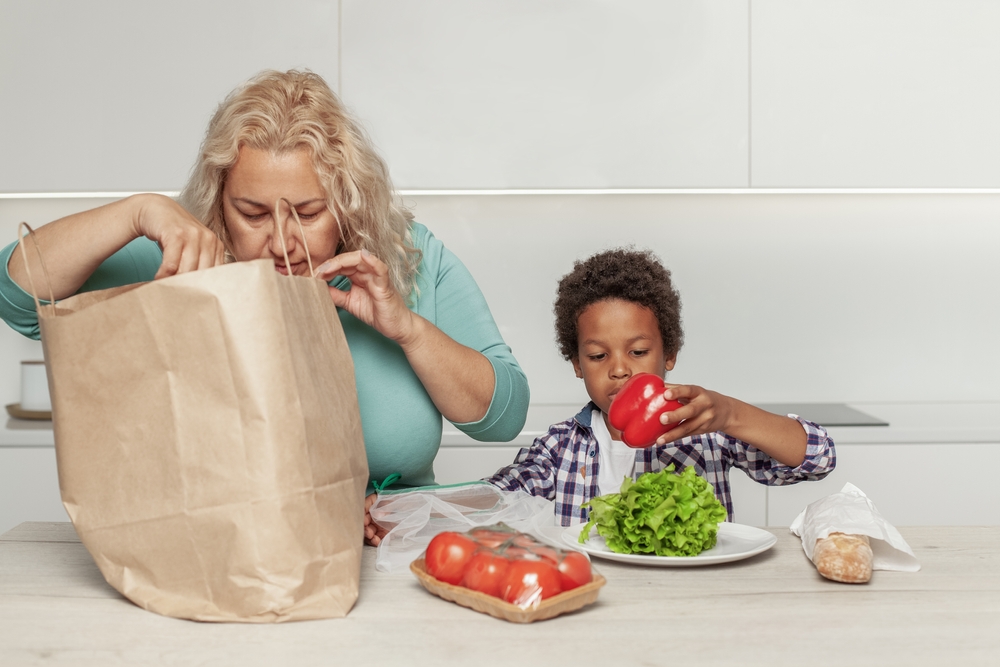 Mom and son taking healthy groceries out of a paper shopping bag.