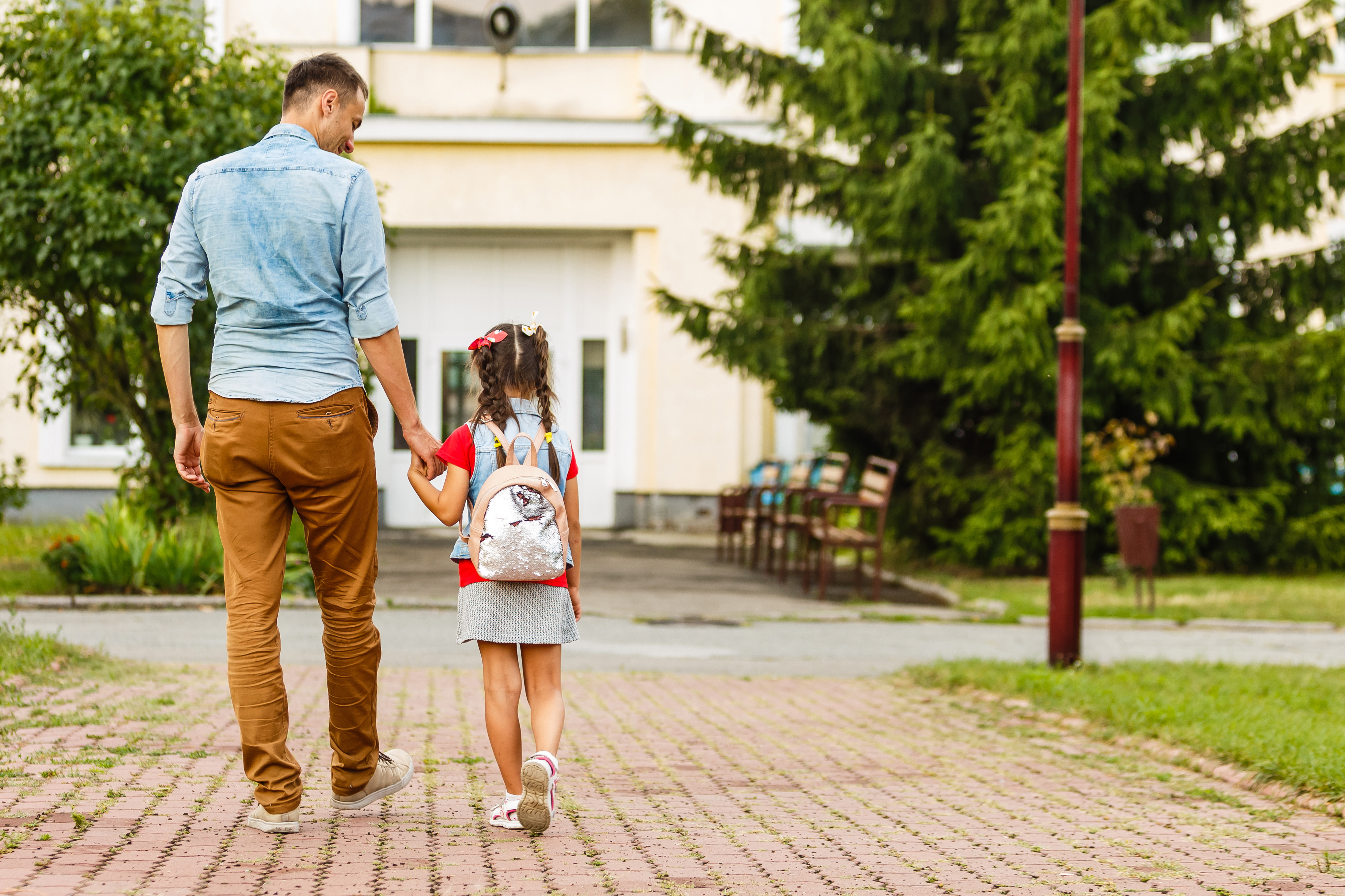 Father leading his daughter to school, holding her hand.