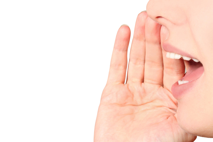 Woman holding hand over mouth shouting.